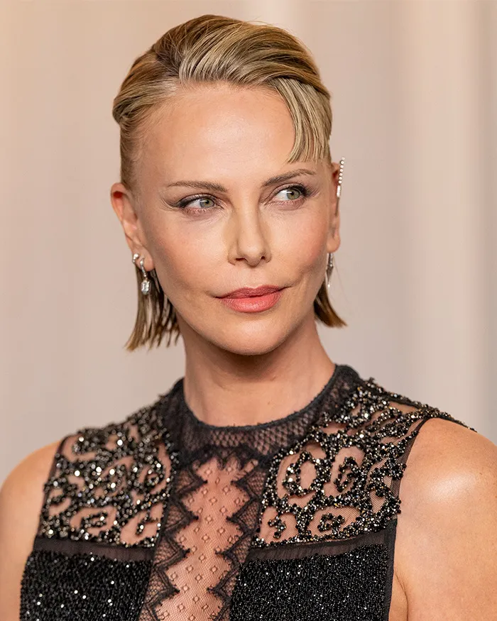 Unedited photo of Charlize Theron at the Academy Museum Gala with short slicked hair.