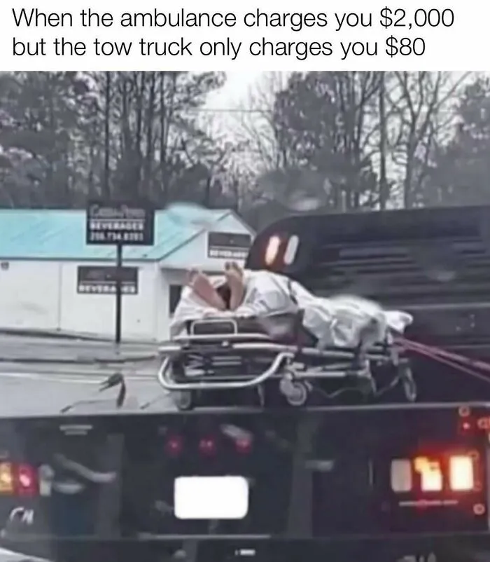 A funny redneck memes scene showing a person lying on a stretcher being transported on the back of a tow truck.