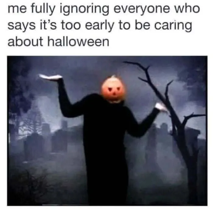 Person wearing a pumpkin head in a graveyard shrugging, representing funny Halloween memes about early celebrations.