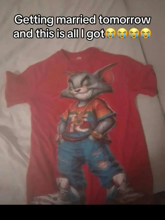 Hilarious pics of a red t-shirt featuring a cartoon cat wearing street clothing laid out on a bed