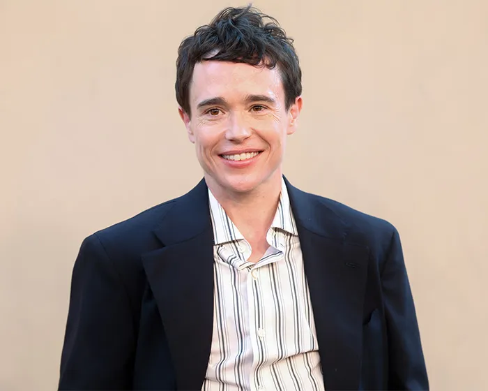 Actor Elliot Page smiling in a suit, highlighted among prominent trans actors in Hollywood.