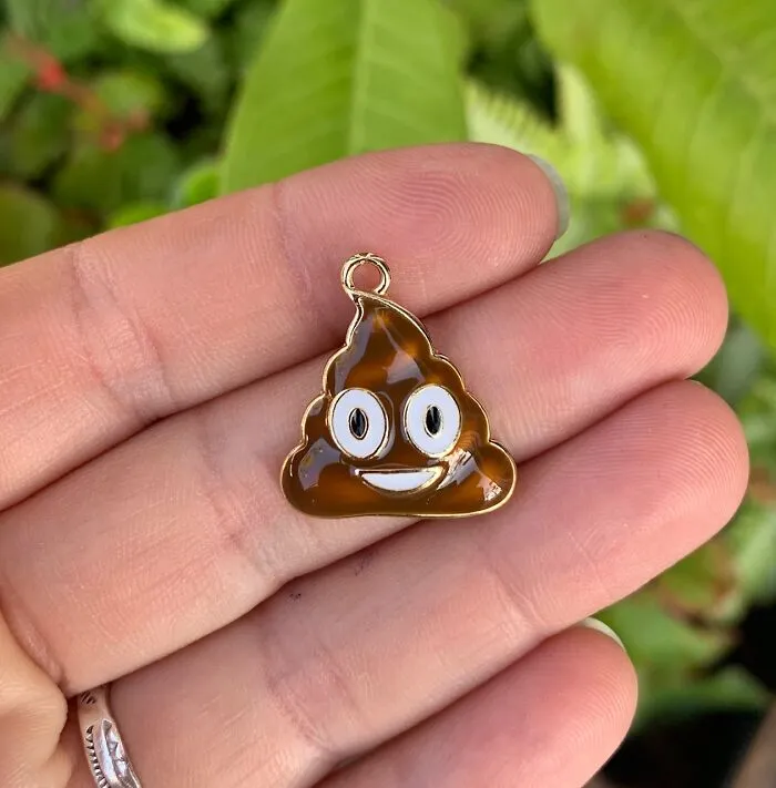 A small smiling poop emoji charm held in a hand