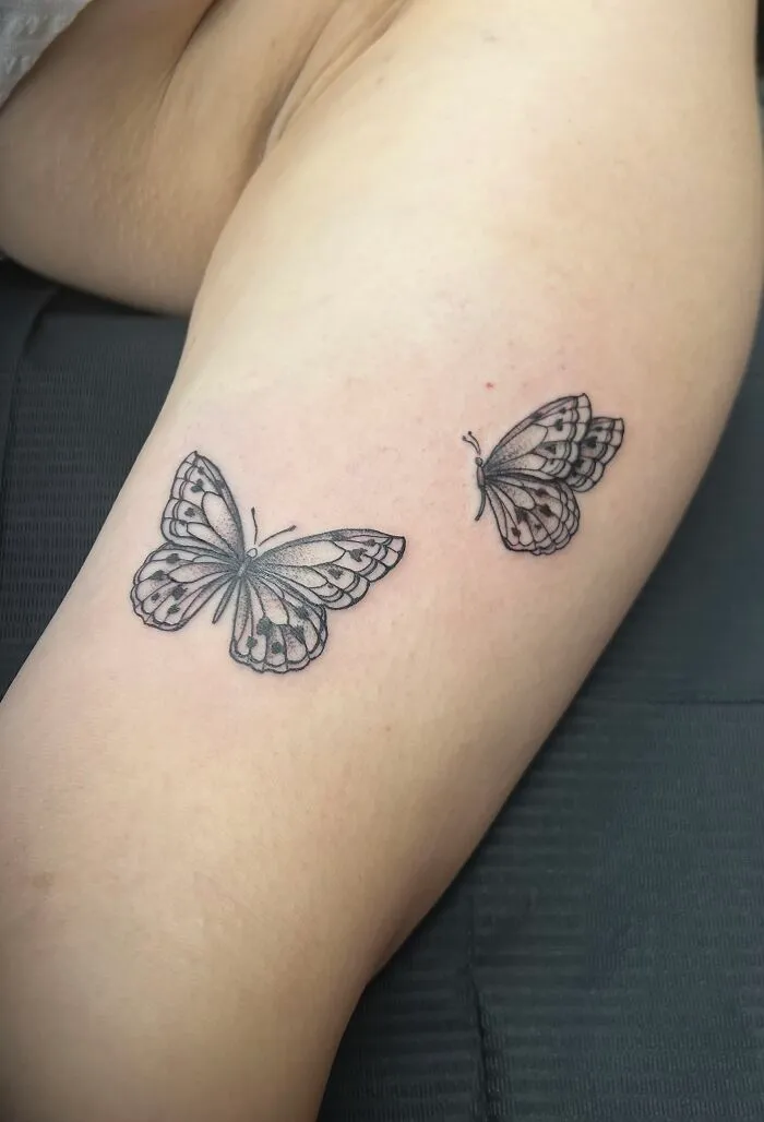 Pair of black and gray butterfly tattoos on thigh