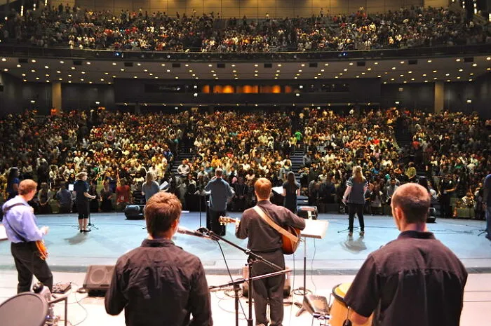 A large crowd gathered in an auditorium watching a stage performance connected to lesser-known cults.