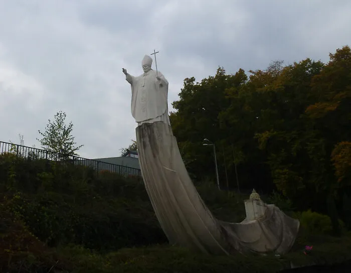 Bizarre public art showing a tall white statue of a Pope standing on a giant curved structure