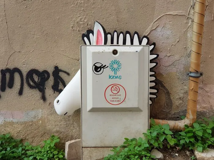 Creative art collective zebra head artwork integrated onto a utility box on a city street.