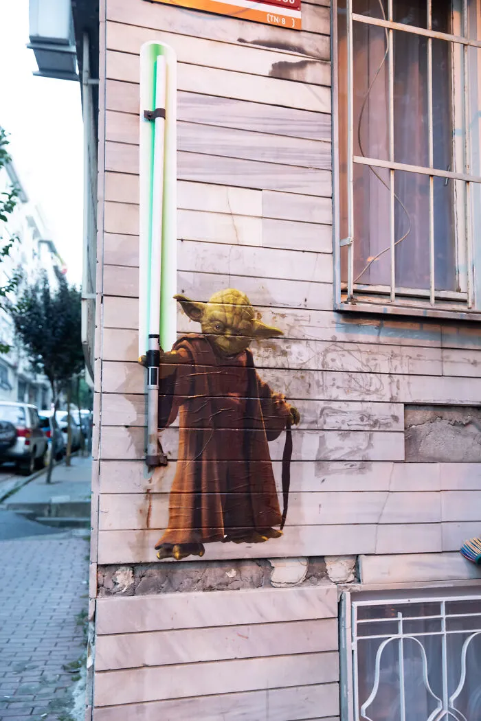 Yoda street art by a creative art collective using a green neon light as a lightsaber