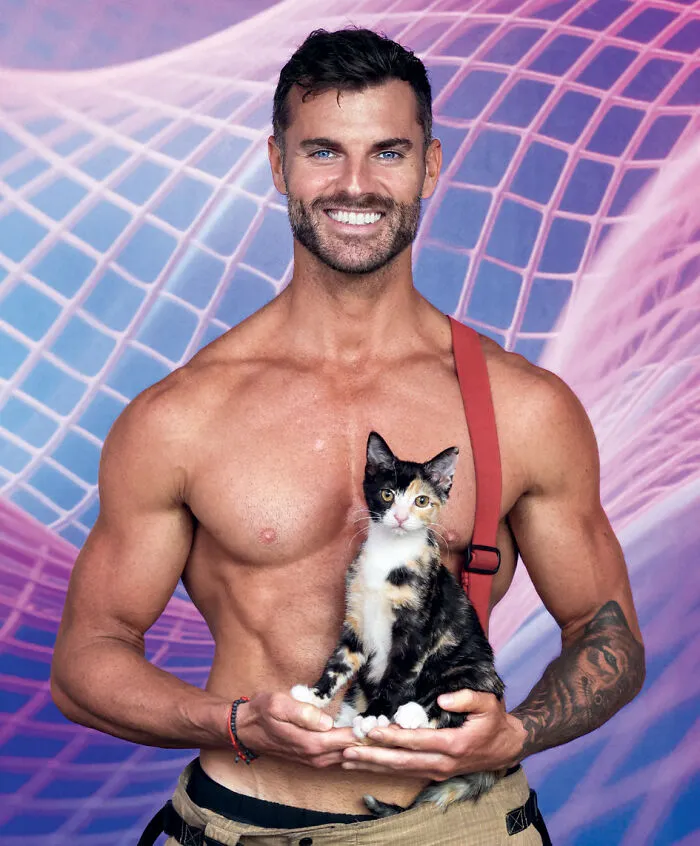 2027 Australian firefighters calendar tattooed firefighter holding calico cat with bright backdrop
