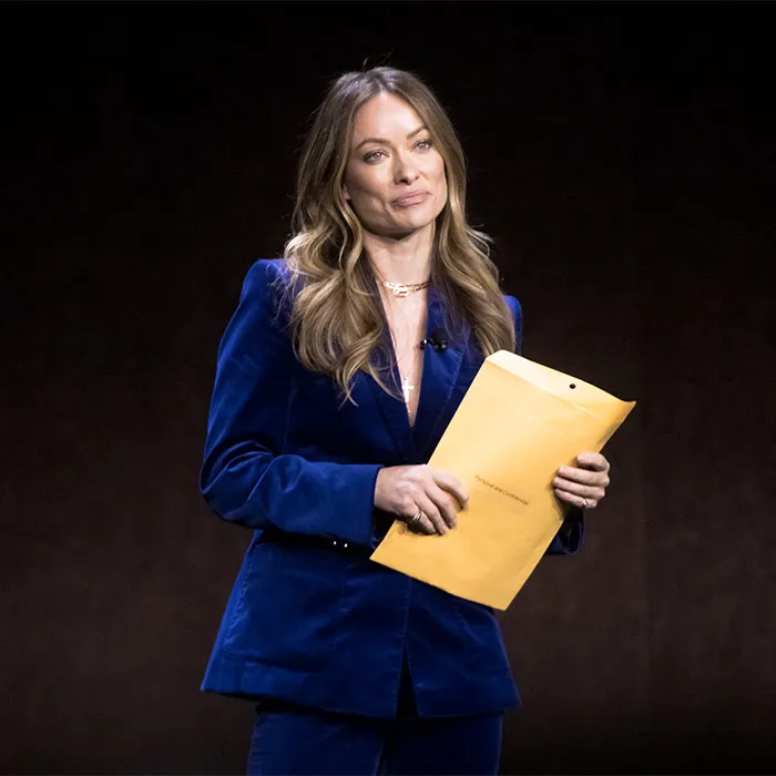Hollywood actress Olivia Wilde holding a yellow envelope on stage