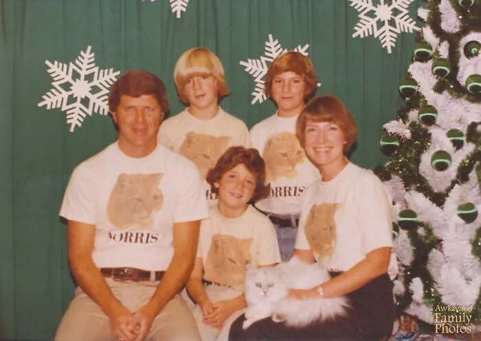 A family wearing matching t-shirts with a cat face on them, posing for unique family photos with cats.