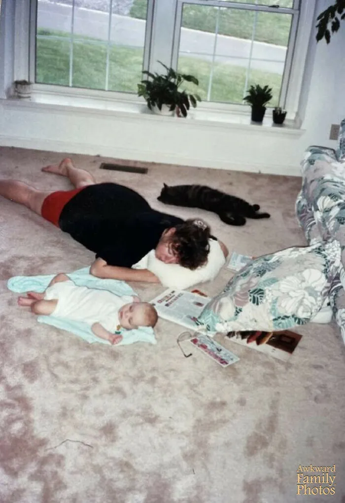 A parent and baby lying on the floor sleeping next to a cat, showing hilarious family photos with cats.
