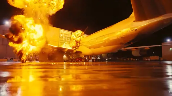 An action movie scene depicting a massive airplane explosion with fiery movie props.