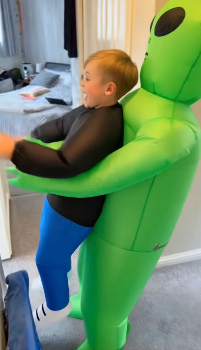 A boy wearing an inflatable green alien abduction outfit as a creative low-effort Halloween costume.