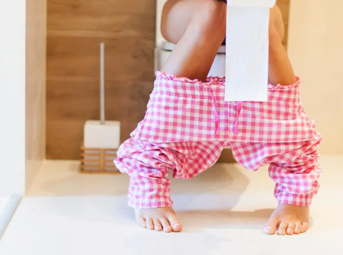 A low angle view of someone on a toilet holding paper discussing myths about women's bodies.
