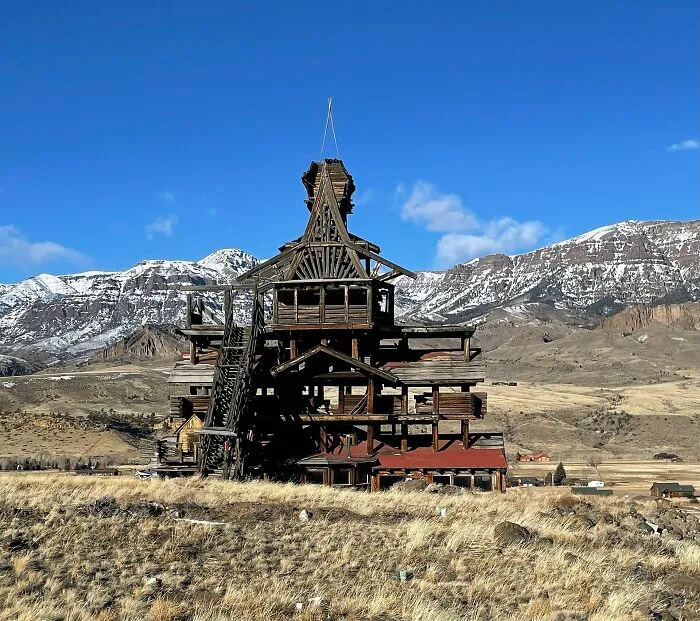 A multi story wooden mansion in a mountain valley showcasing bizarre shapes.