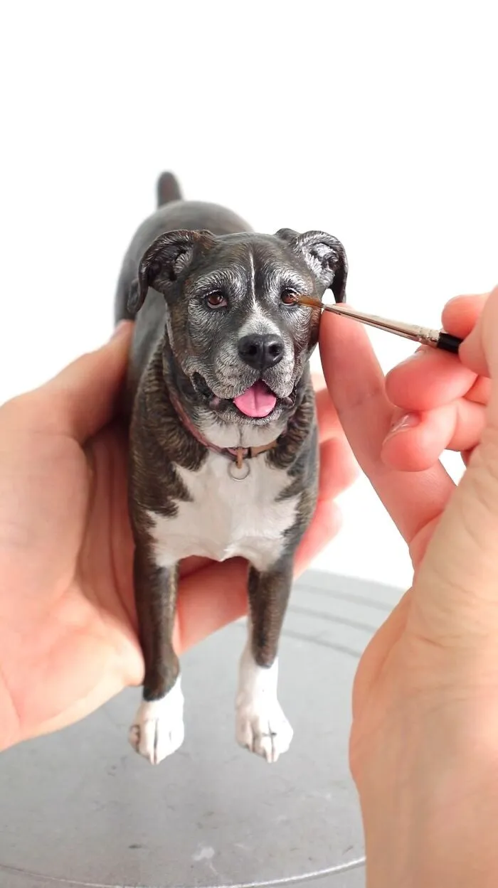 Artist painting fine details on a hyperrealistic sculpture of a dog.