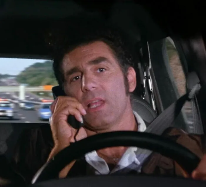 Michael Richards on the phone in a car, representing stars who got in the way of their own success.