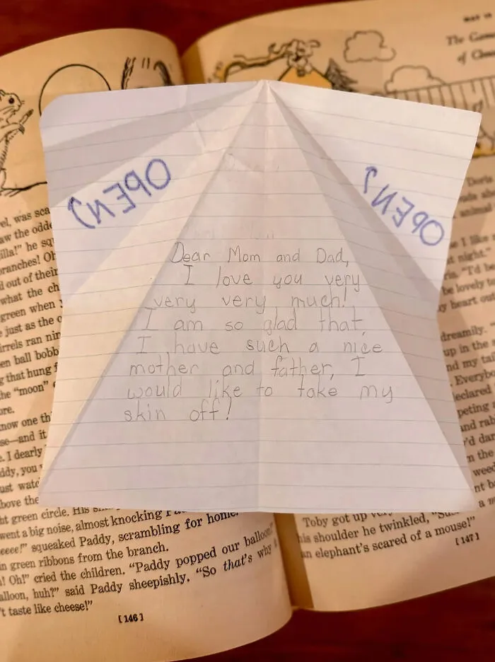 Found paper note with handwritten message to parents lying on top of an open book.