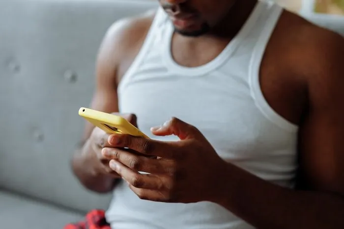 A man looking closely at his mobile phone screen to find secrets shared on the internet