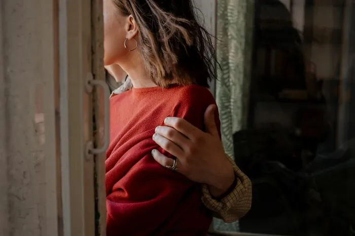 A man puts a supportive arm around a woman in a red sweater, sharing a secret moment together