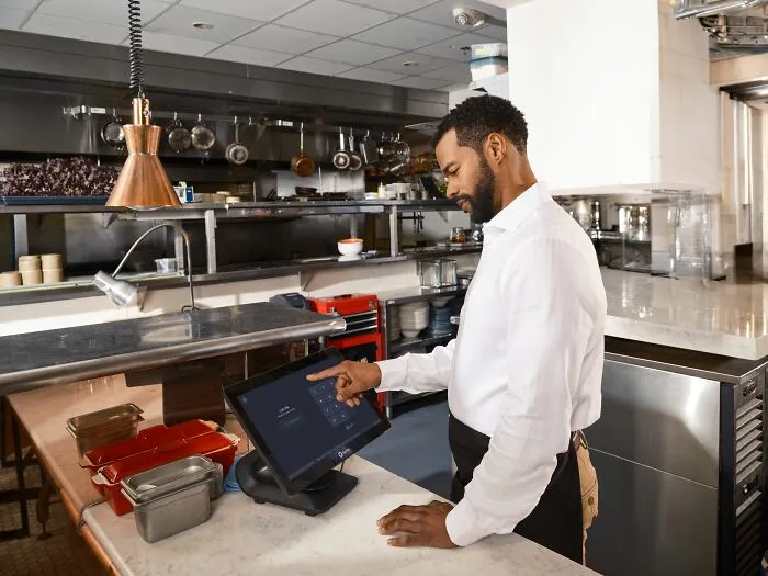 A chef using a digital POS tablet screen in a kitchen to find secrets