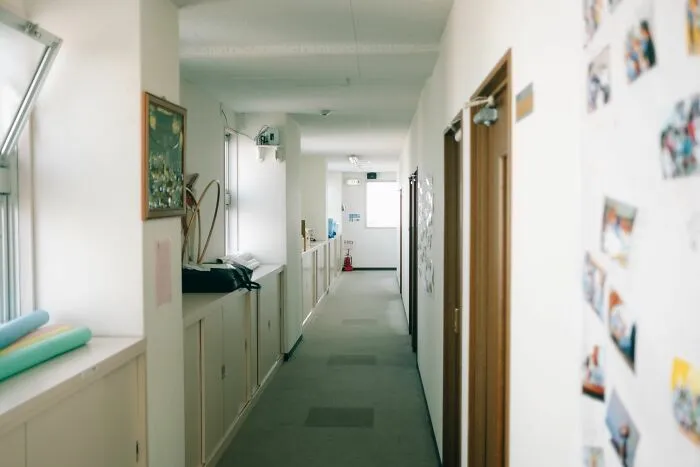 A long empty office hallway with white walls and closed doors containing secrets shared