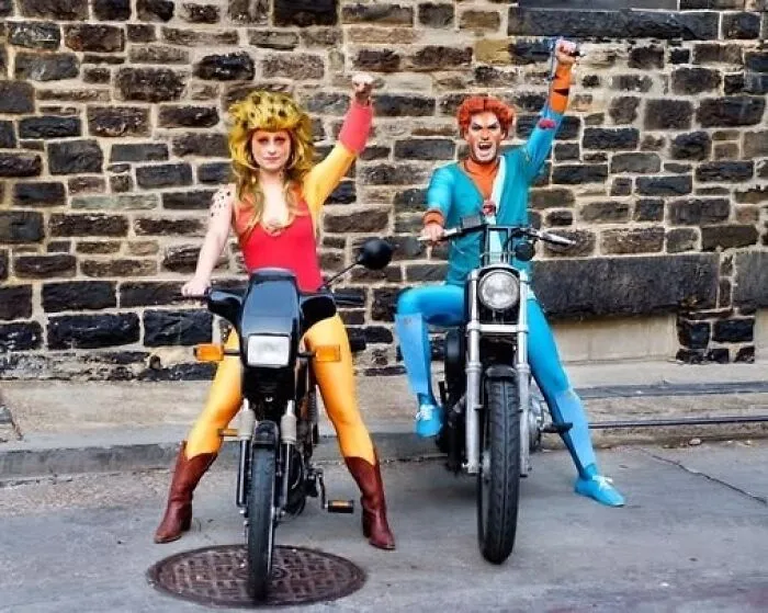 Man and woman posing on motorbikes in bright funny cool halloween couples costumes