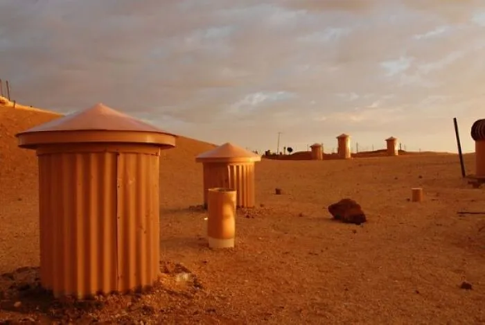 Rust-colored cylindrical structures in desert landscape