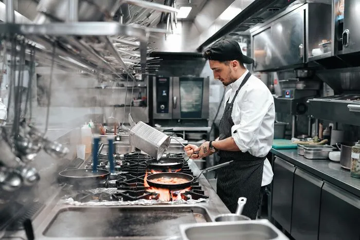 Chef cooking in a busy commercial kitchen, showing industry insiders behind the scenes at restaurants.