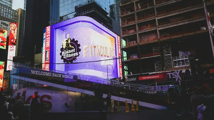 A glowing Planet Fitness billboard in Times Square highlighting wild stories in city life.