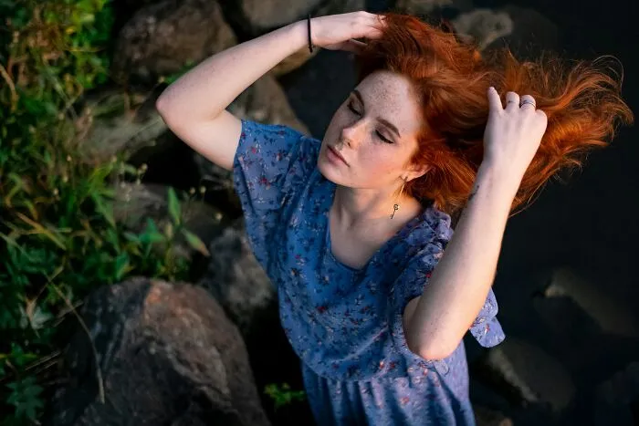 A redhead woman running her hands through her hair after hearing what strangers said.