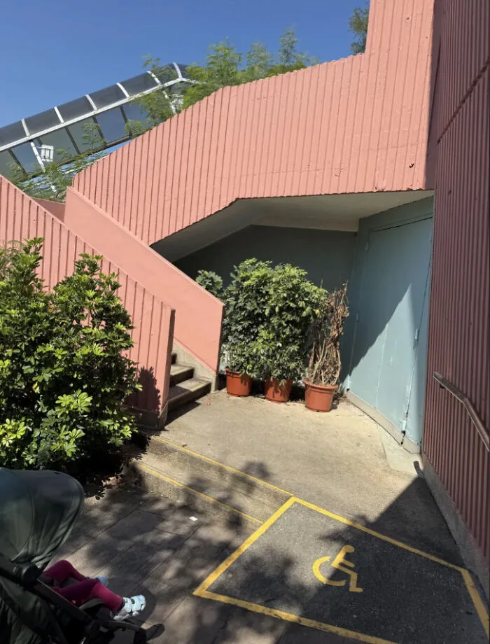 Outdoor pink staircase blocking the accessible wheelchair ramp entrance