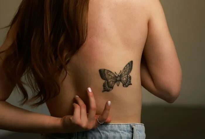 Woman showing a butterfly tattoo on her back, highlighting unique partner stories and intelligence questions.