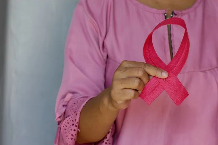 Close-up of a person holding a pink ribbon, debunking Hollywood tricks about quick medical recoveries