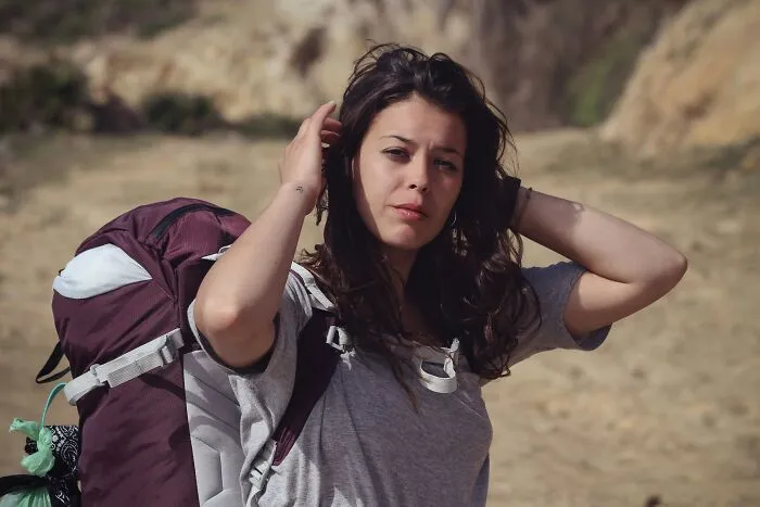 A female hiker holding her hair, listening to her gut feeling during a trek.