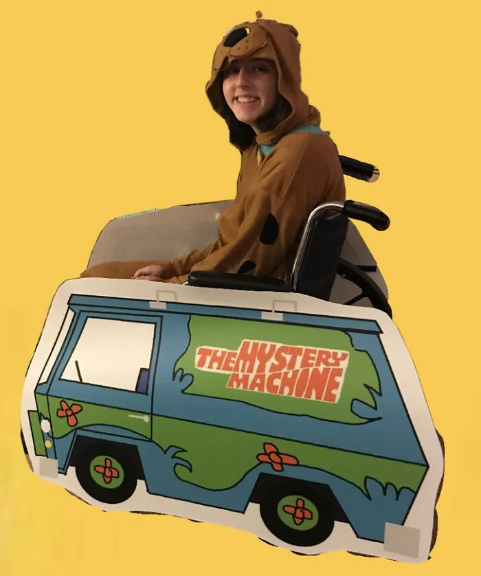 Person in Scooby-Doo costume in a wheelchair styled as Mystery Machine for Halloween.
