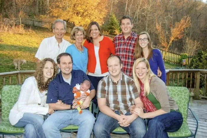 Family photo where a dog in the background completely hijacked the moment while pooping on the lawn.