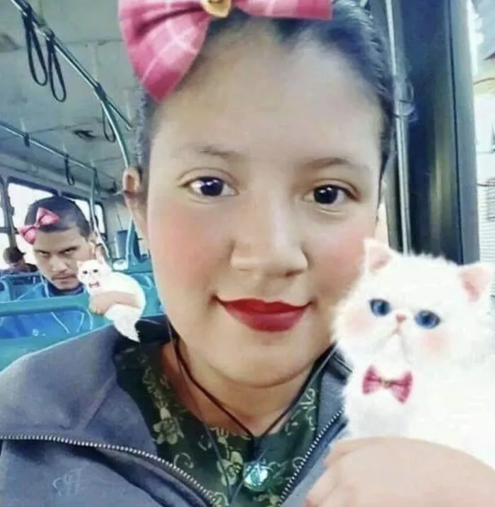 Background completely hijacked the moment by a passenger in a blue jacket holding a white cat behind a girl.