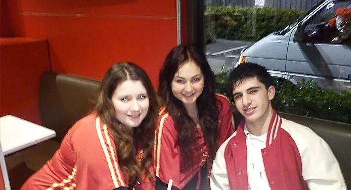 A scary figure in a car window in the background of a friends group photo.