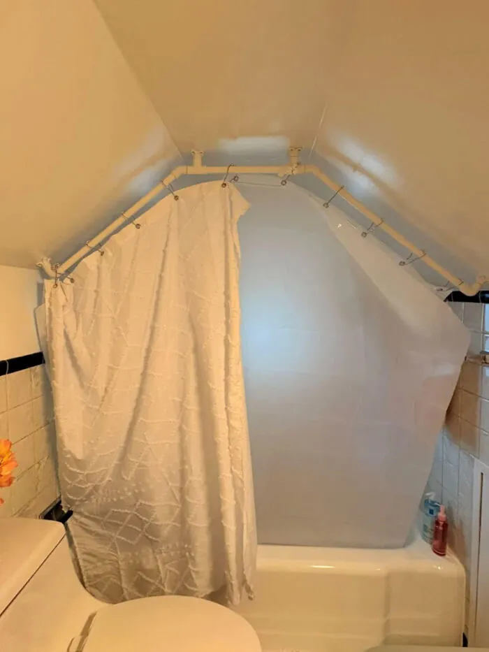 Bathroom with awkwardly shaped shower curtain rod under sloped ceiling