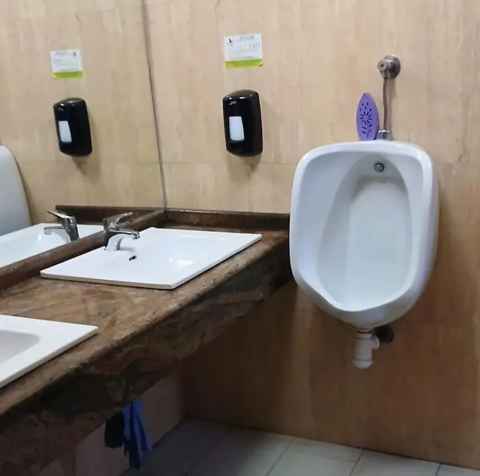 urinal installed next to bathroom sink causing awkward design