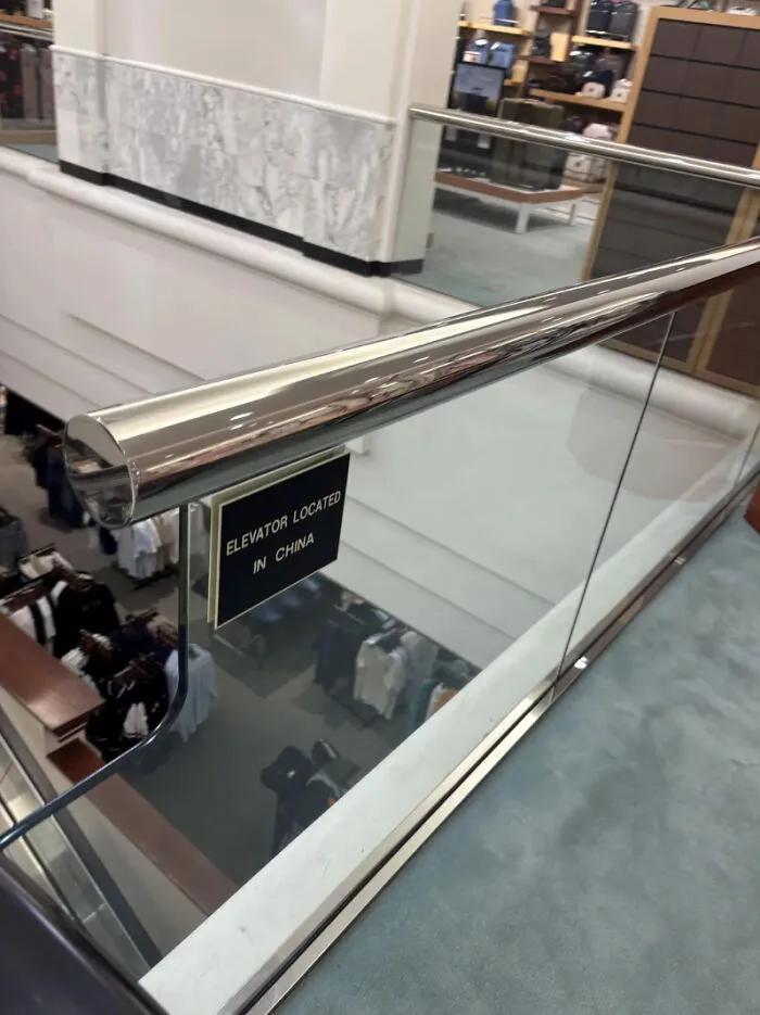 Mall railing with a misplaced elevator location sign creating design confusion