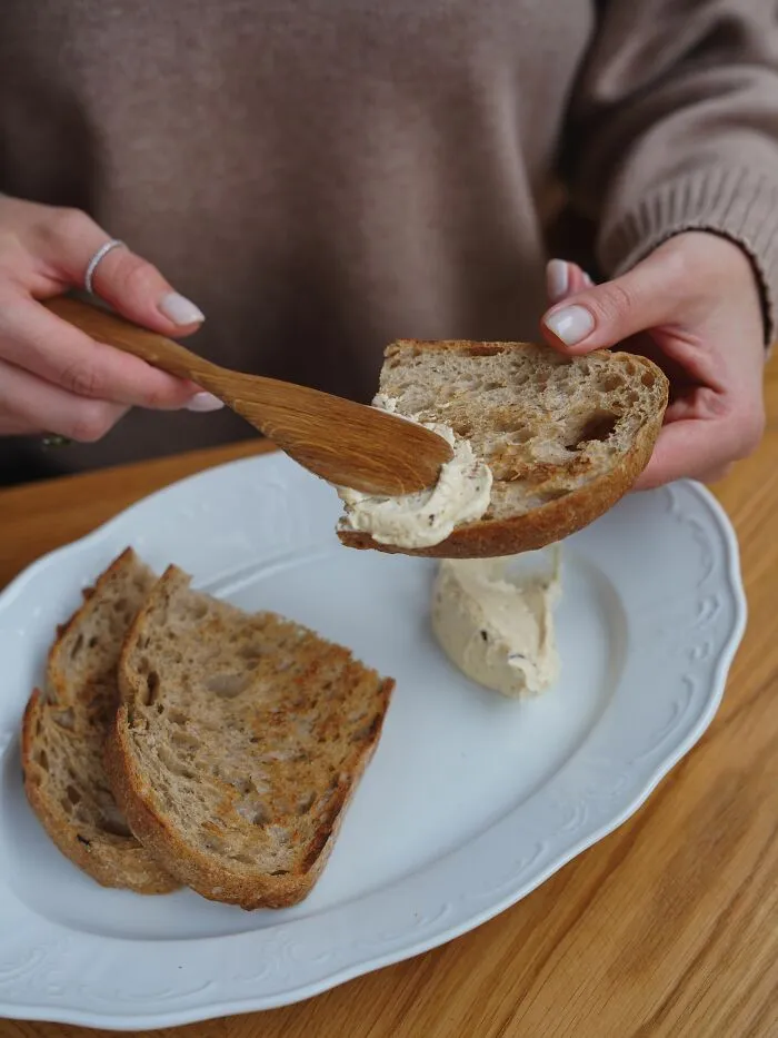 Spreading cream cheese on toasted bread slice illustrating basic life skills
