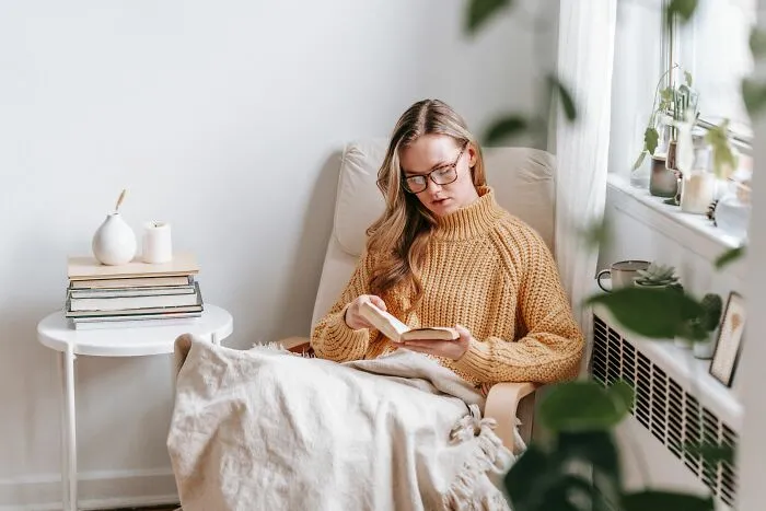 Woman reading a book sitting in armchair practicing basic life skills