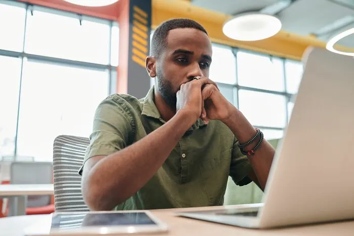 Man thinking deeply while working on laptop showing life skills