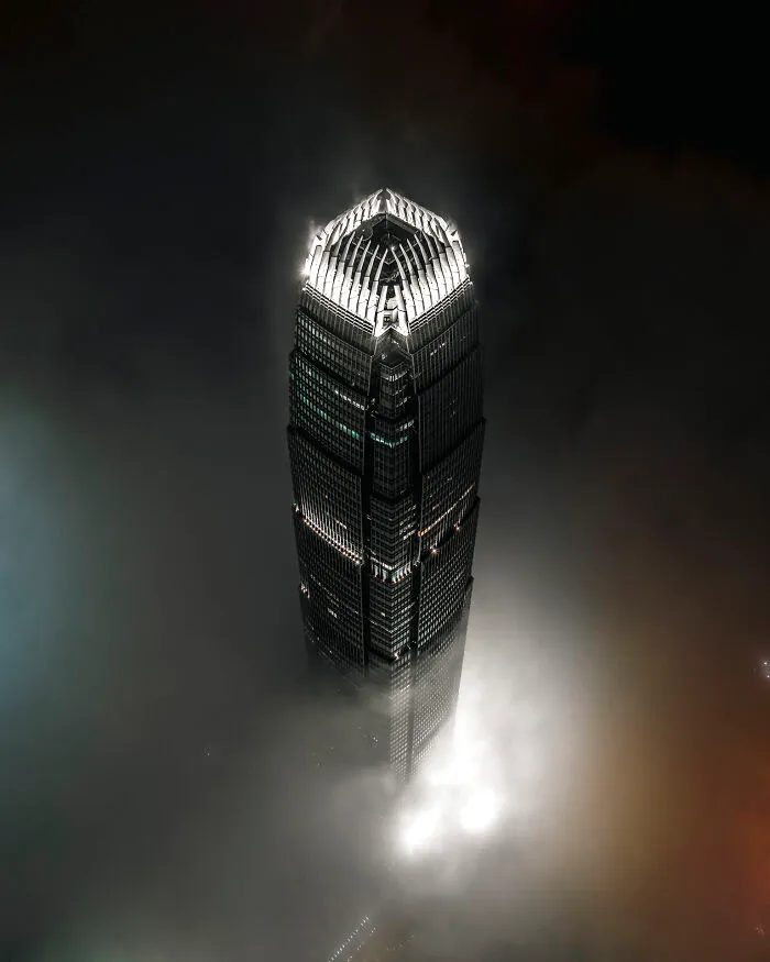 A modern skyscraper rising above a thick layer of clouds, illustrating the beauty of buildings and spaces