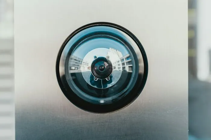 Close-up of a home security peephole camera on a metal door