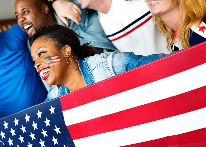 Cheerful group holding an American flag, sharing laughs over intelligent insults.