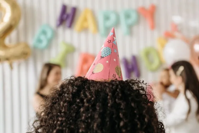 Back of a person wearing a pink party hat at a birthday celebration representing intelligent insults.