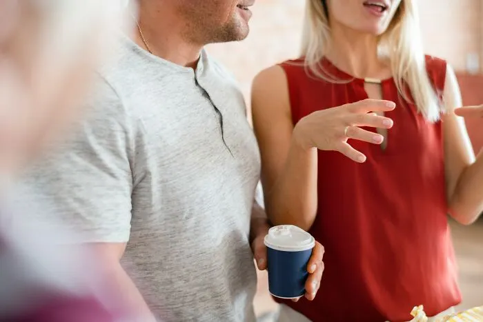 A man and a woman conversing at an event, sharing intelligent insults over coffee